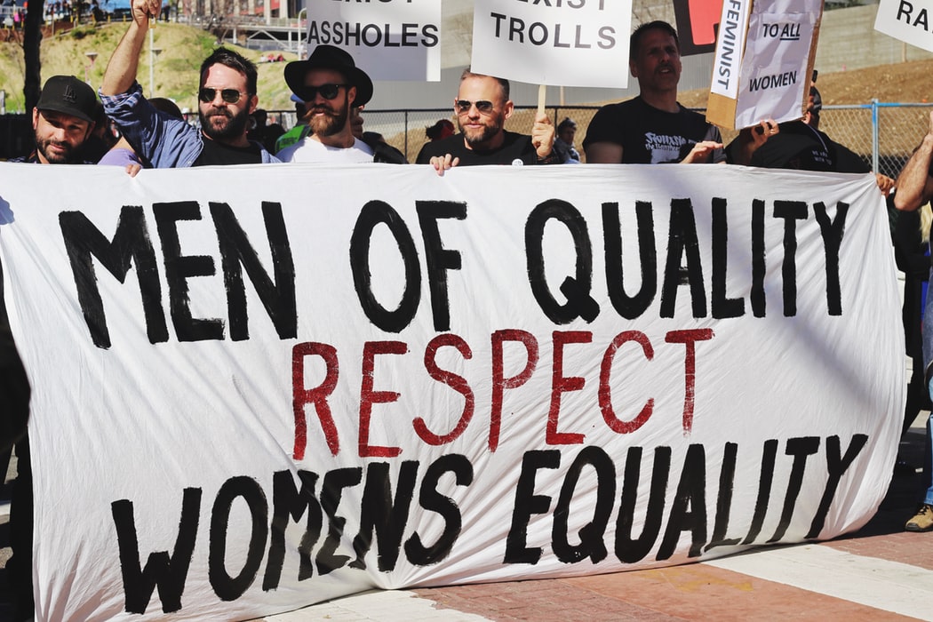 Men holding a banner written "Men of quality respect women's equality".